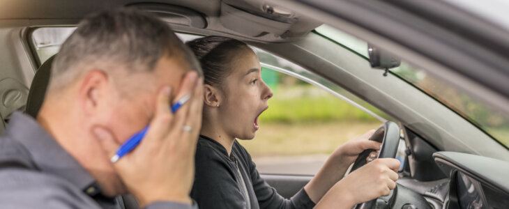 Failed Driving test. Young serious inexperienced woman driving a car in alert, worried instructor man sitting aside and looking nervous at the road, dangerous situation. Fearful driving instructor or father and student. Car accident
