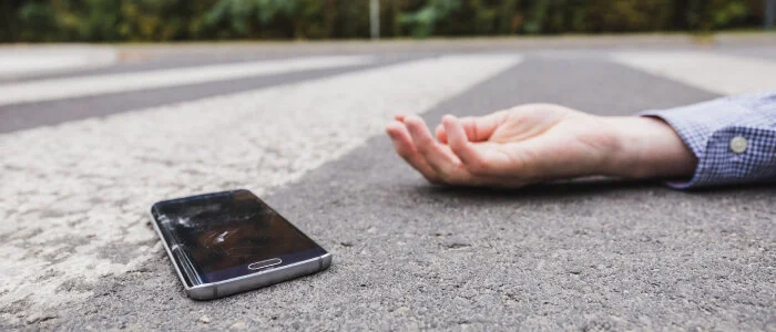 A man lays on road next to his phone