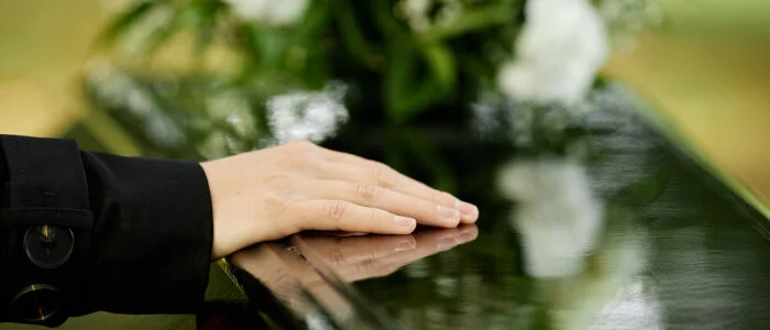 A man puts his hand on a coffin