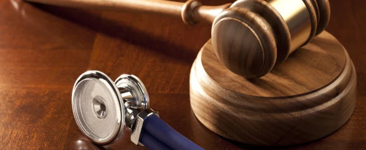 Judge’s gavel and stethoscope on a wooden table, symbolizing medical malpractice law
