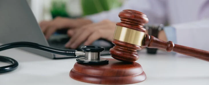 Gavel With Medical Stethoscope while doctor using laptop, Concept of medical law and medical crimes.