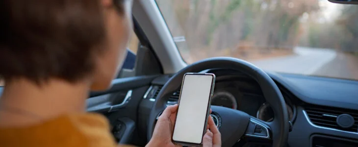 Mockup image of a woman holding and using mobile phone with blank screen while driver a car. People, Driving, Navigation and Transportation Concepts