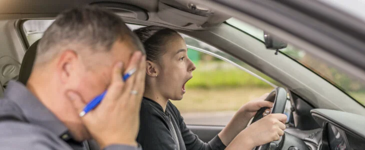 Failed Driving test. Young serious inexperienced woman driving a car in alert, worried instructor man sitting aside and looking nervous at the road, dangerous situation. Fearful driving instructor or father and student. Car accident